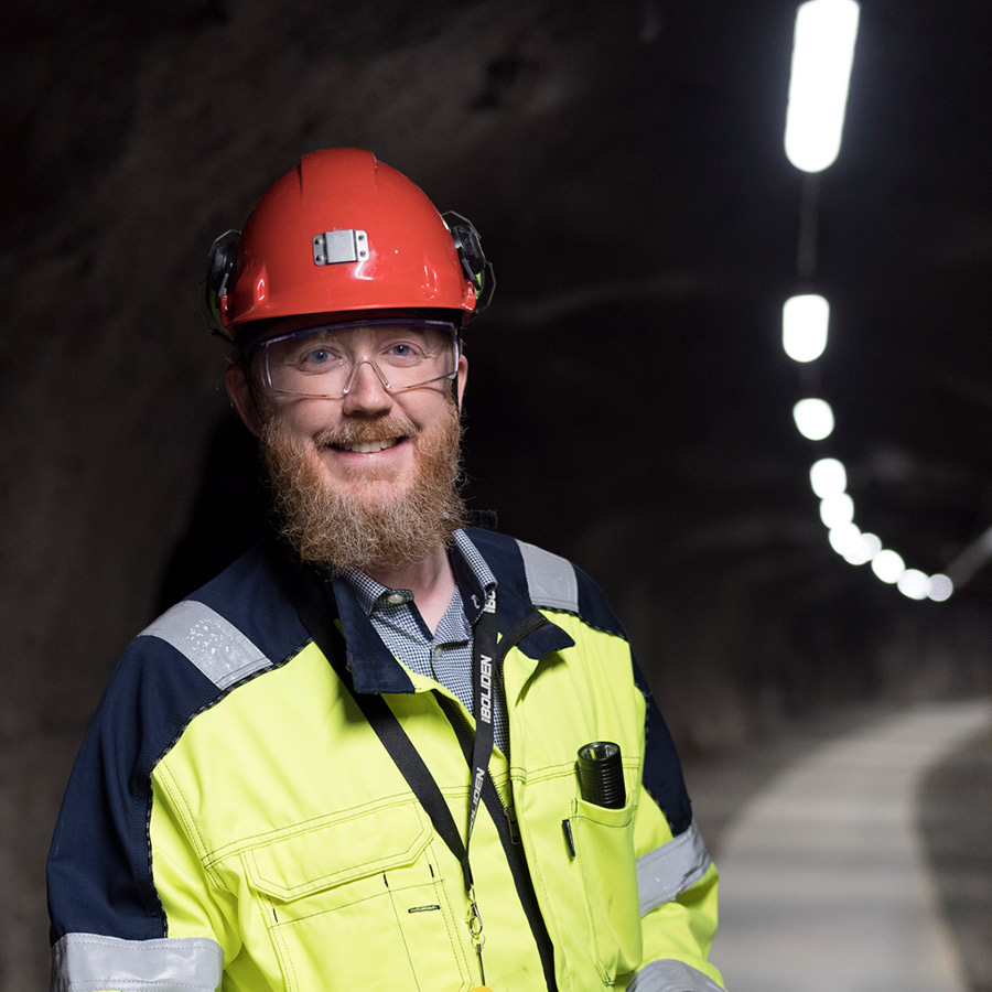 Andreas Stenlund seisoo suojavarusteissa kaivoskäytävällä ja hymyilee.