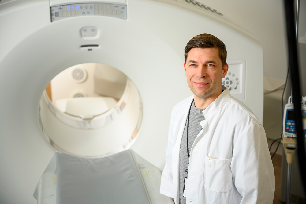 PET-keskuksen järjestelmäasiantuntija Rami Mikkola seisomassa PET-kuvauslaitteen edessä.