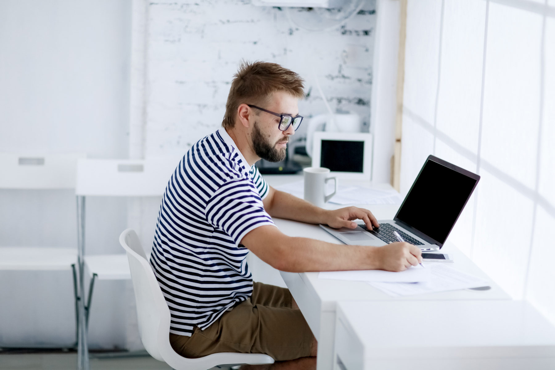 Mies käyttää tietokonetta toimistossa