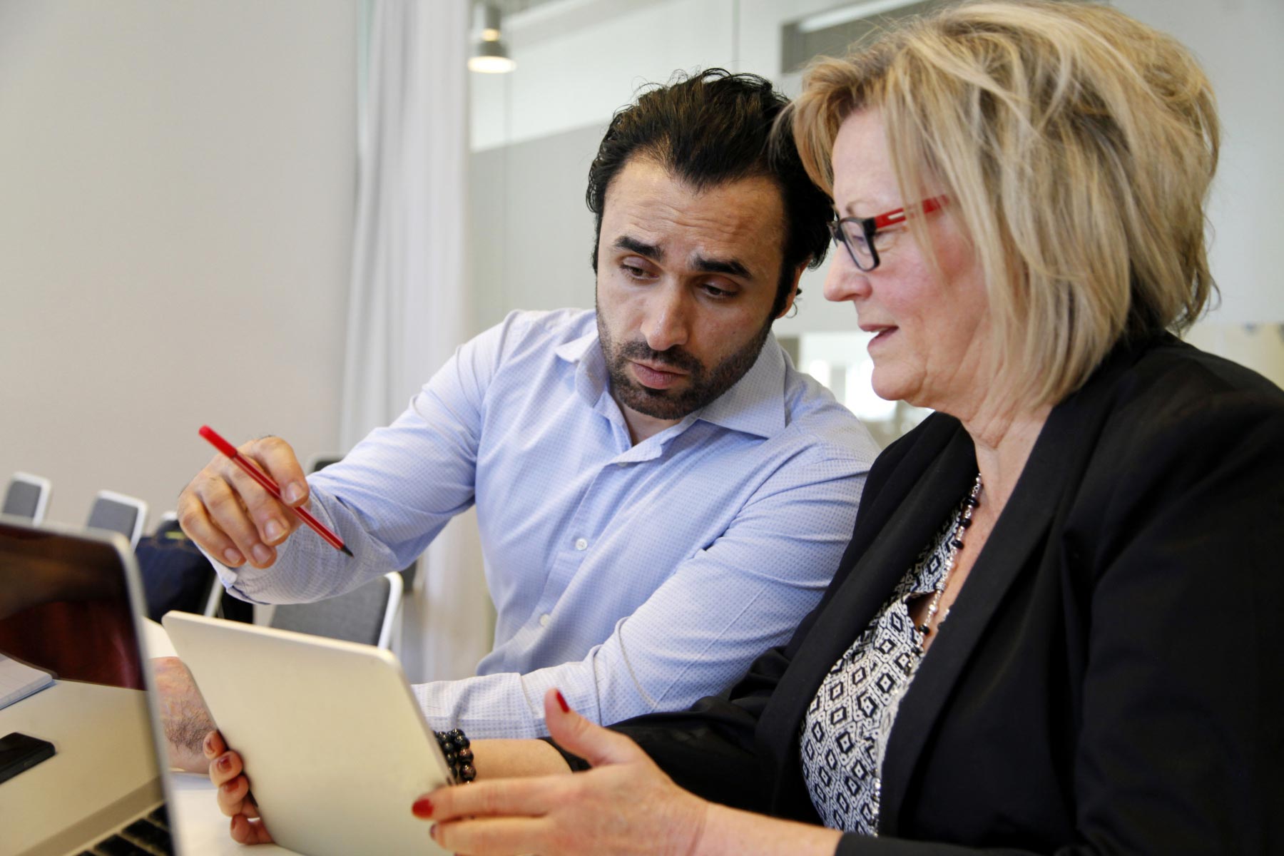 Mies ja nainen keskustelevat, mies osoittaa naisen tabletilla olevaa asiaa.