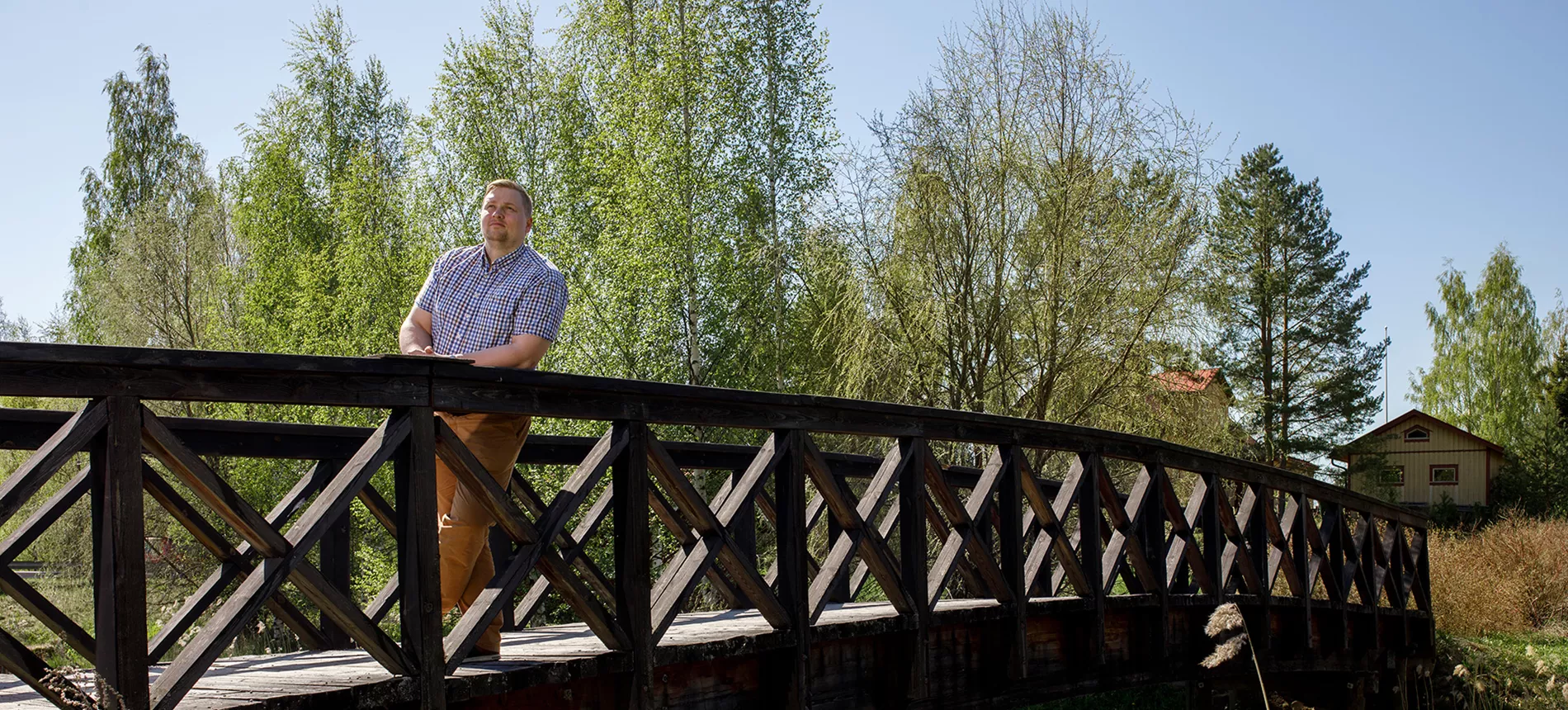 Luhangan kunnanjohtaja Tuomo Kärnä joen ylittävällä sillalla kesäisessä maisemassa.