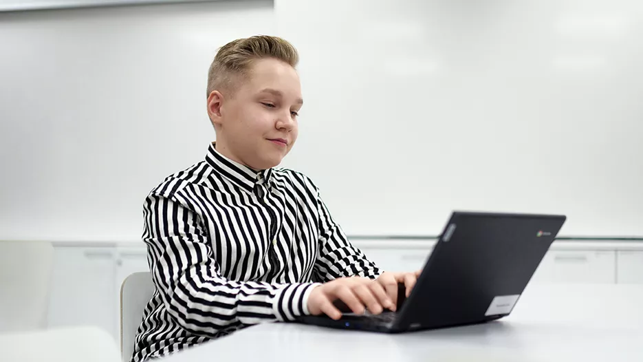 Tiera Verkkokauppa referenssi, Parkanon Kaarna koulukampus. Poika, jolla on raitapaita, käyttää tietokonetta.
