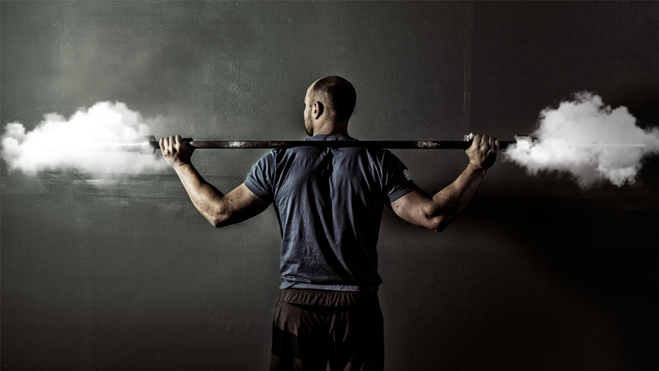 Painonnostaja, jolla tanko selässä. Tangon päissä levyjen sijaan pilvet.