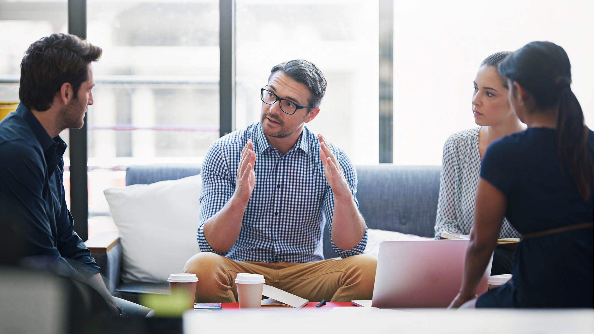 Kaksi miestä ja kaksi naista istuvat sohvaryhmässä keskustelemassa keskittyneesti.